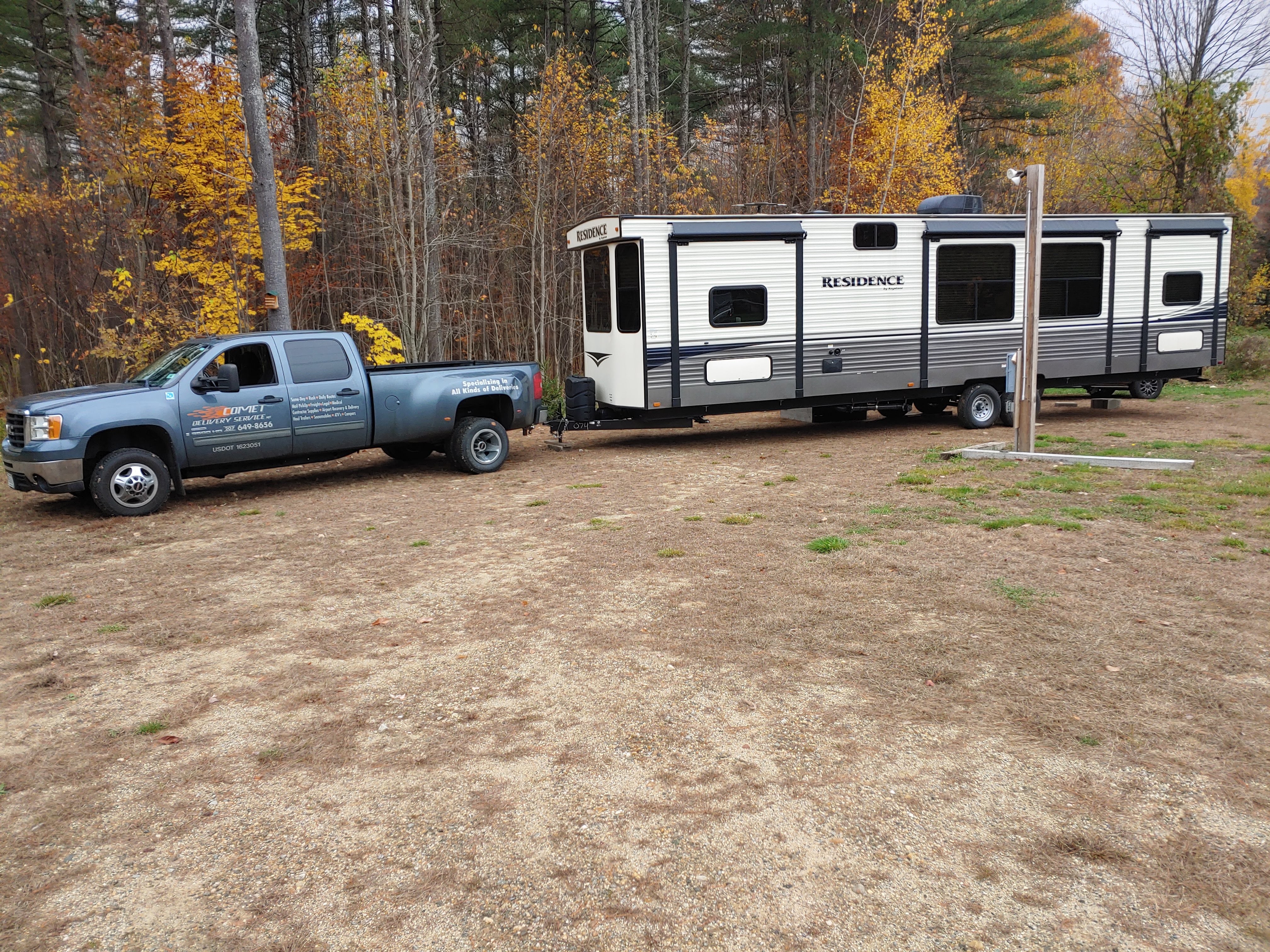 Comet Couriers hauling a residence-style RV trailer through autumn Maine woods