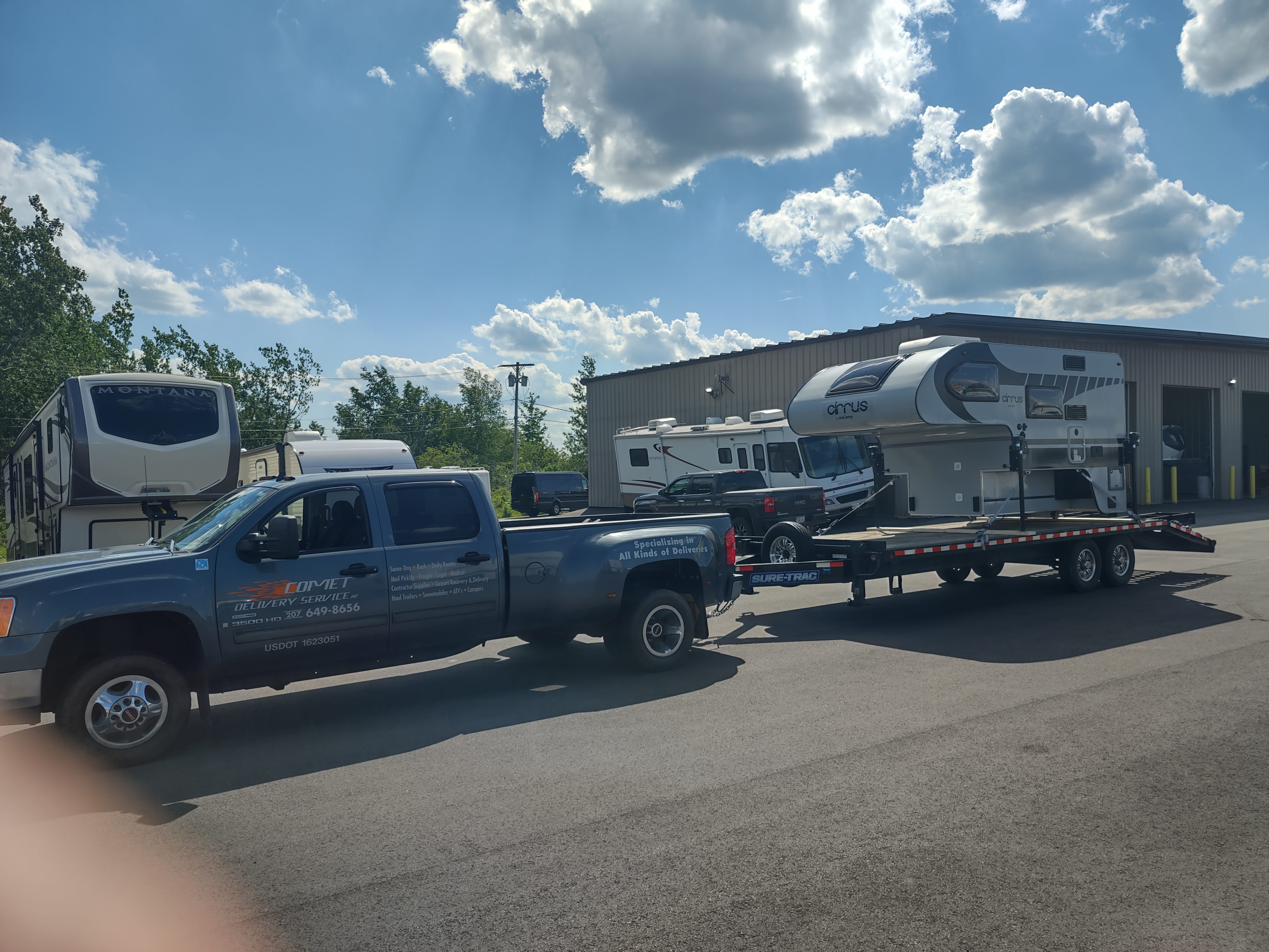 Comet Couriers towing an RV camper on a flatbed trailer